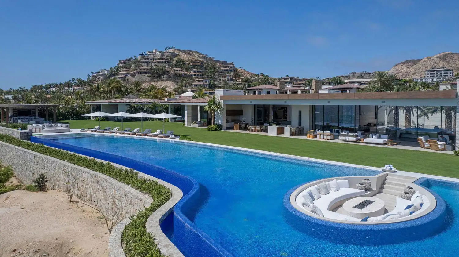 The long curved pool, lawns and main house of Casa Elije, a ten-bedroom rental villa in Palmilla, Los Cabos