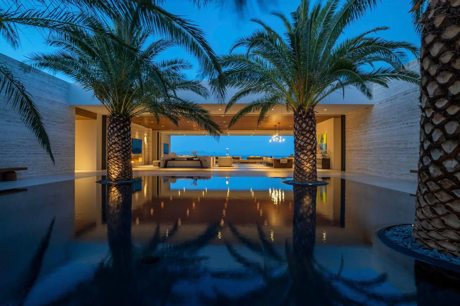 The pool terrace and palms of Casa Elije at dusk, a rental villa in Palmilla, Los Cabos