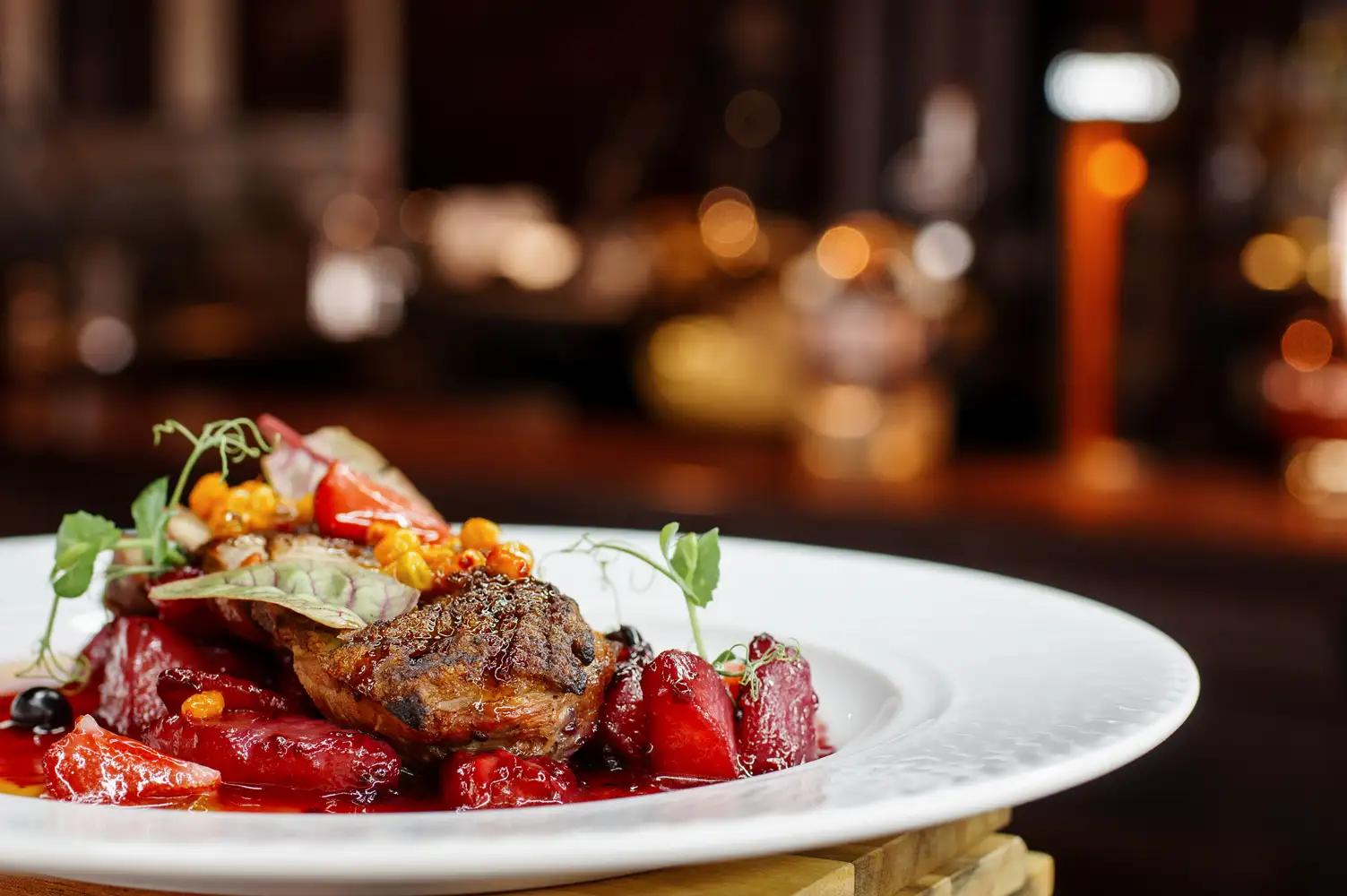 A plated main course with vegetables and garnishes in a restaurant.