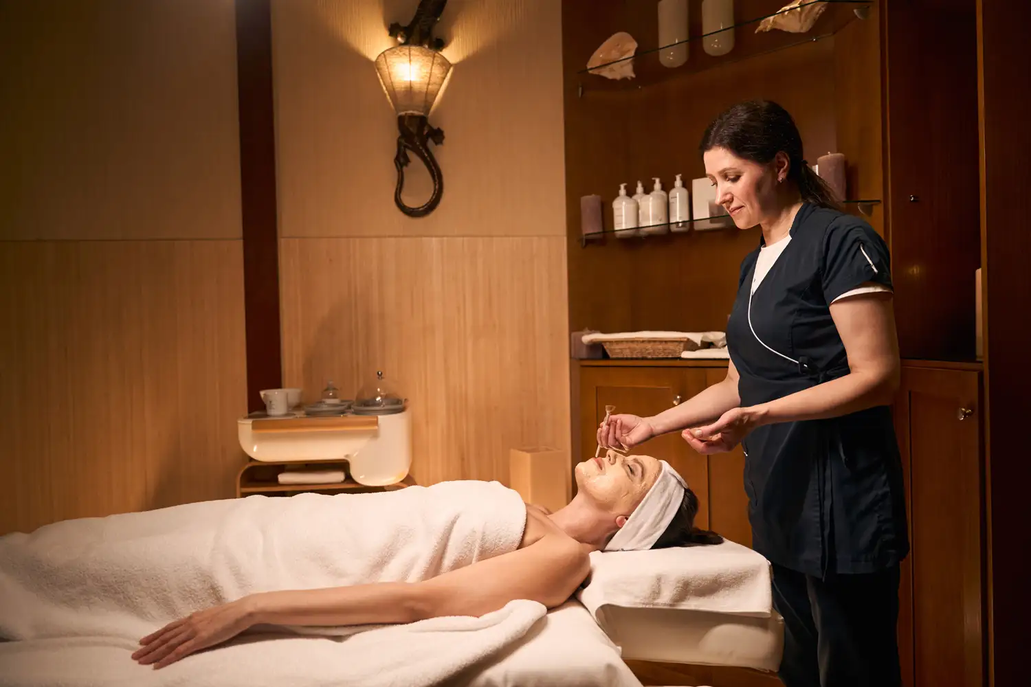 A therapist providing a facial treatment in a spa room.